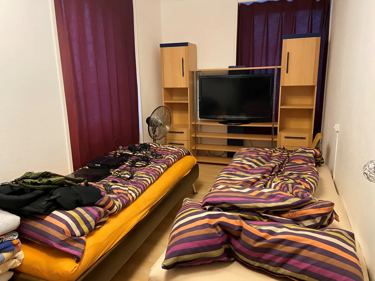 Ein Zimmer mit zwei schmalen Einzelbetten und einem Fernsehmöbel